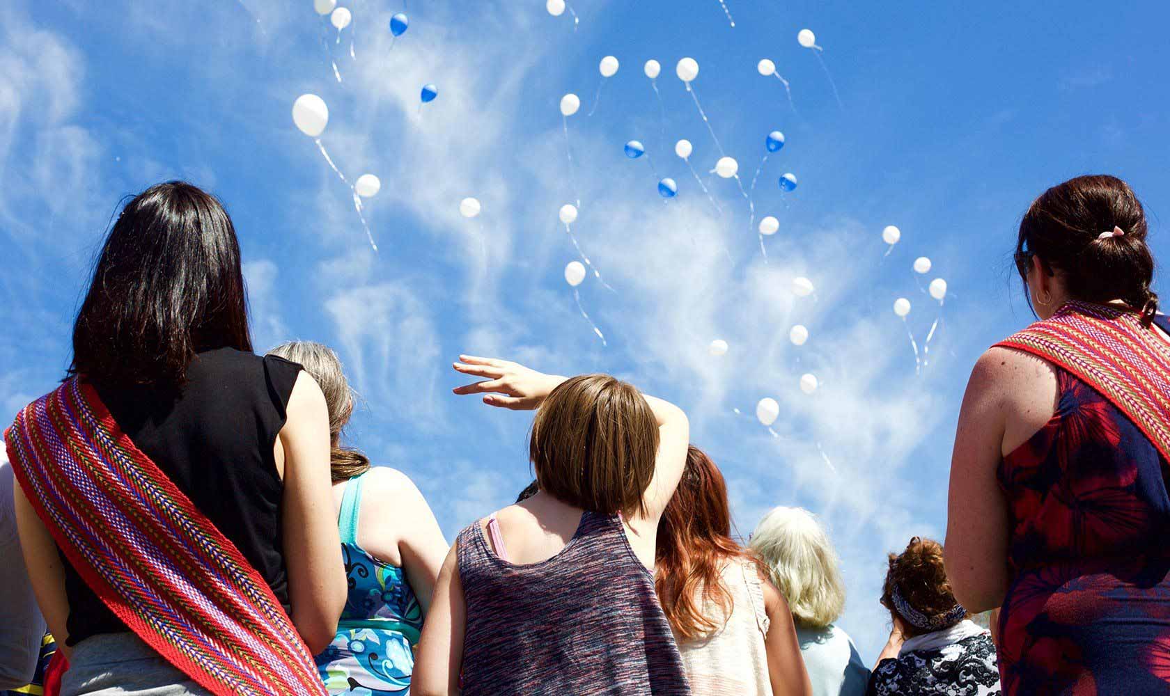 A group of youth releasing balloons into the sky.